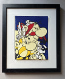 Three comic characters – Asterix with yellow moustache, Obelix with red hair and the white haired Dogmatix – have a happy hug on a blue background