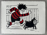 Dennis in his red and black football jersey runs in front of a fence, with gnasher by his side