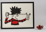 dennis menace from the beano comic in red and black jersey fires his catapult. approved by publisher dc thomson